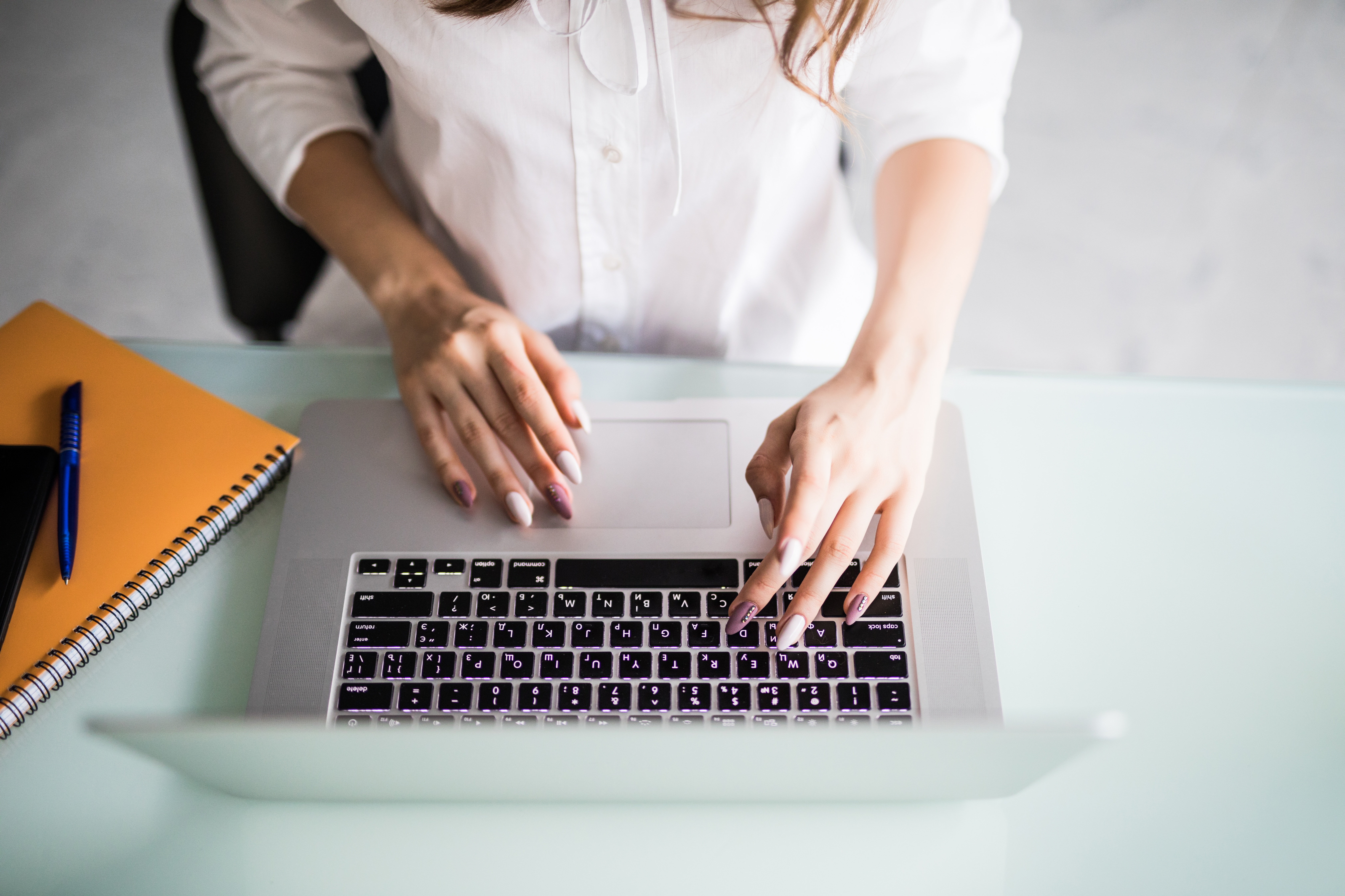 Widok z&nbsp;g&oacute;ry na&nbsp;kobietę pracującą przy laptopie w&nbsp;nowoczesnym, jasnym biurze.
