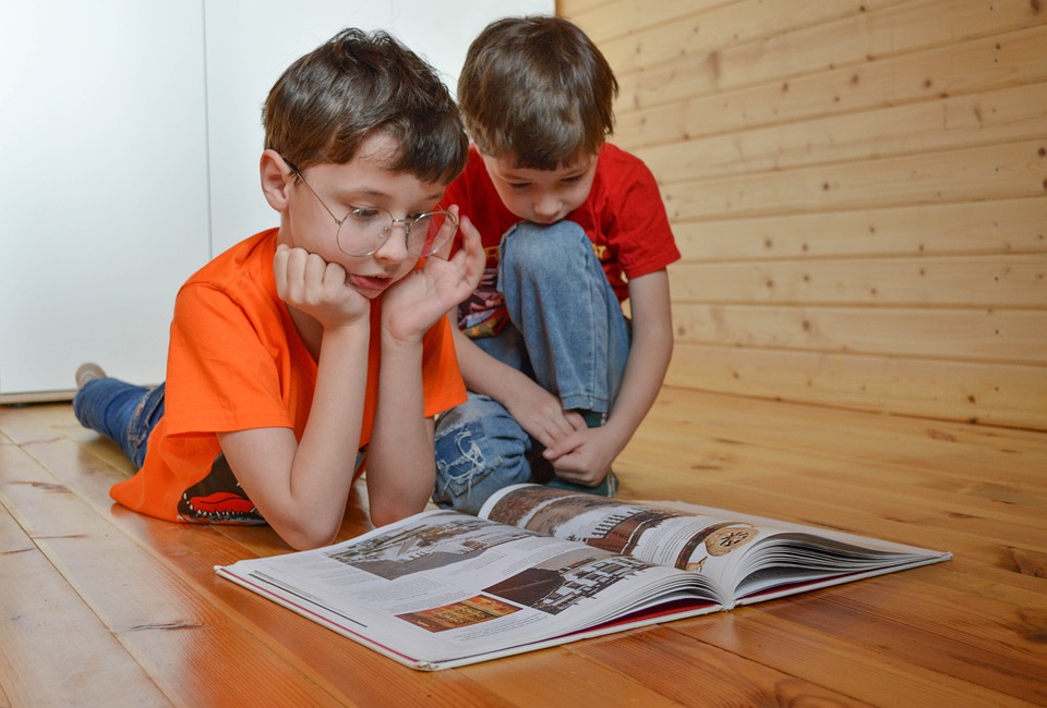 Dwójka dzieci w pokoju oglądająca książkę z ilustracjami
