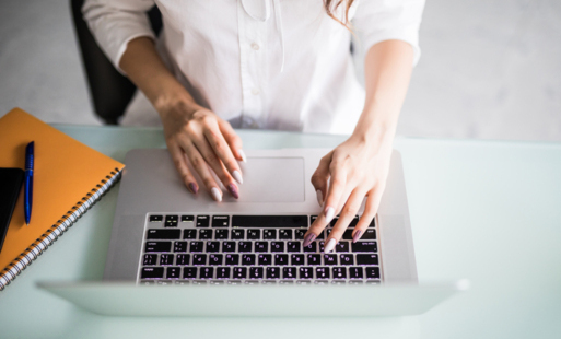 Widok z góry na kobietę pracującą przy laptopie w nowoczesnym, jasnym biurze.