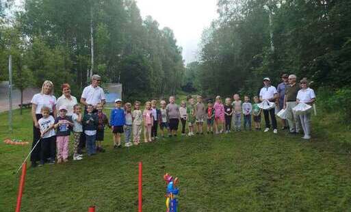 Dzieci i seniorzy pozują do zdjęcia na polu golfowym 